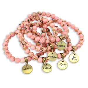 Pink beaded necklace with gold charm pendants on a white background