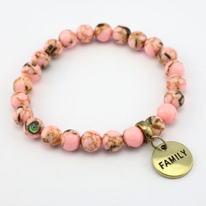 Bracelet with pink beads and a 'FAMILY' charm on a white background