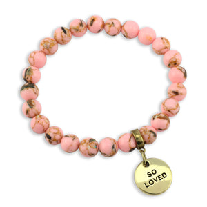 Pink beaded bracelet with a gold 'SO LOVED' charm on a white background
