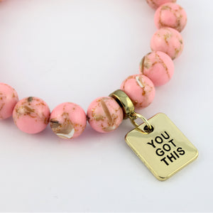 Pink beaded bracelet with a gold 'YOU GOT THIS' charm on a white background