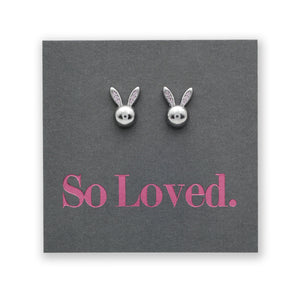 Sterling silver stud earrings in the shape of a rabbit face with pink CZ detailing, presented on a grey card with the text 'So Loved' in pink.