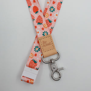 Be Kind embossed on a pink strawberry and flower lanyard with tan trim and a lobster clasp.