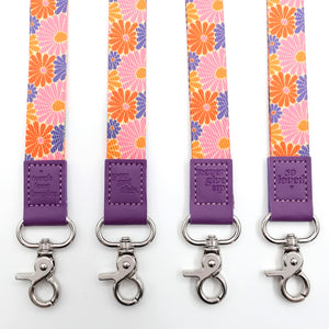 Four floral lanyards with purple ends and silver hooks on a white background.