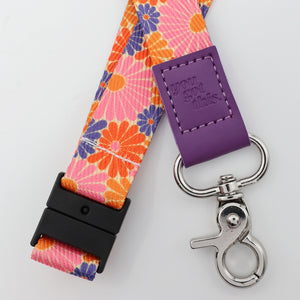 Floral lanyard with purple tag and silver clasp on a light gray background