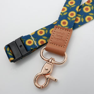 Teach Love Inspire embossed on a navy sunflower lanyard with brown trim and a lobster clasp.