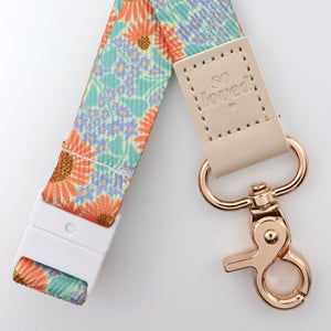 Floral patterned lanyard with a rose gold keychain on a light background