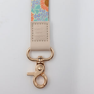 Lanyard with floral strap and gold clasp on a light gray background