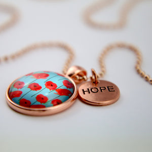 Necklace with a pendant featuring red poppies and a 'HOPE' tag on a light background
