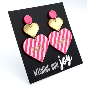 Heart-shaped earrings with pink and gold design on a card with 'Wishing you joy' text.