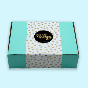 Gift box with teal lid and white polka dot pattern on a light blue background