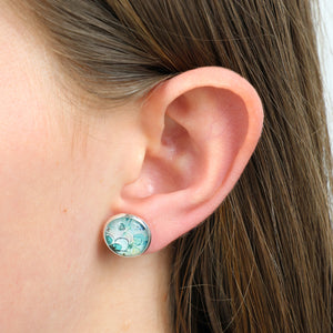 Close-up of an ear wearing a round turquoise earring.