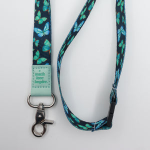 Teach Love Inspire embossed on a navy lanyard with teal butterflies and mint trim and a lobster clasp.