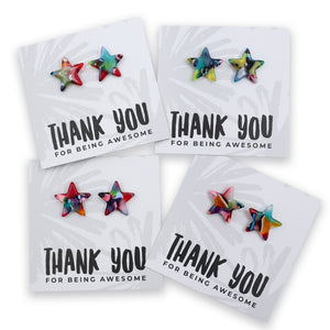 Four star-shaped stud earrings displayed on white backing cards that read 'THANK YOU FOR BEING AWESOME.' The earrings have a multicolor tie-dye pattern with shades of blue, green, pink, orange, and purple.