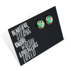 Pair of earrings on a black card with motivational text