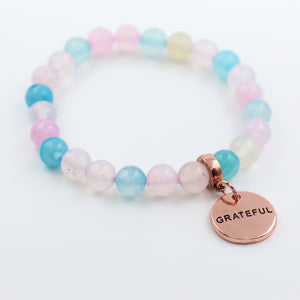 Multicolored beaded bracelet with a 'GRATEFUL' charm on a white background