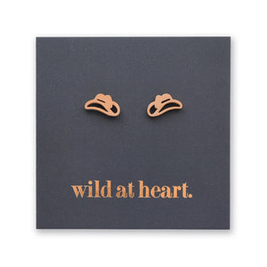 Rose gold cowgirl hat earrings on a black card with 'wild at heart.' text
