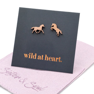 rose gold horse earrings on a black card with 'wild at heart.' text on a mauve pouch