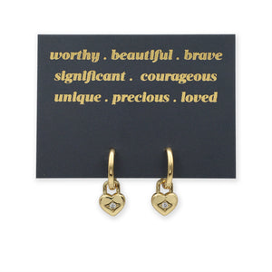 Gold heart-shaped earrings on a black card with gold text.