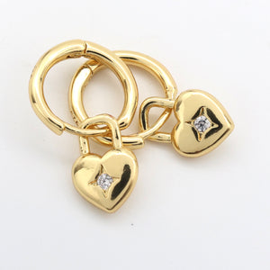 Gold heart-shaped charm with diamonds on a white background