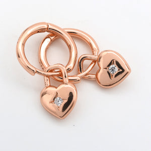 Rose gold heart-shaped charms with diamonds on a white background