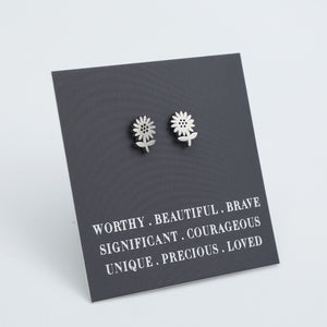 Silver flower earrings on a dark card with motivational text