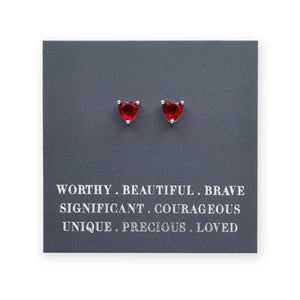 Red heart-shaped earrings on a dark gray card with motivational text