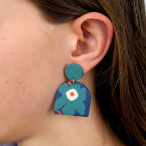 Close-up of a person wearing a blue floral earring.