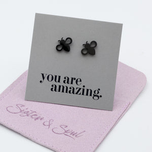 Black bee stud earrings displayed on a gray card that reads 'you are amazing.' with a purple jewelry pouch underneath on a white background.