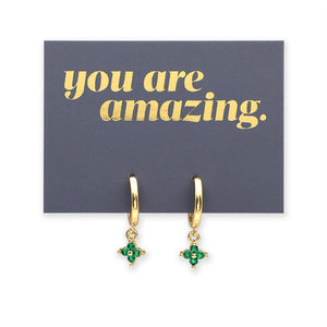 Gold hoop earrings with green gemstones on a card with 'you are amazing' text.