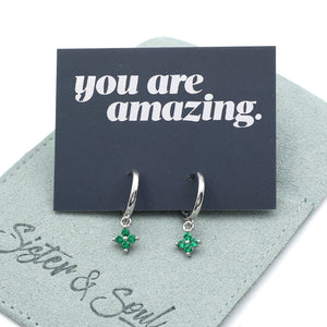Silver earrings with green gemstones on a card that says 'you are amazing' with a gray background.