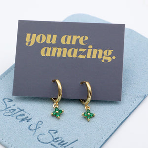Gold huggie earrings with green stones on a 'you are amazing' card