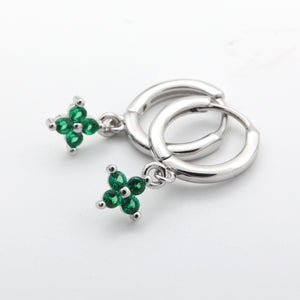 Silver earrings with green gemstones on a white background