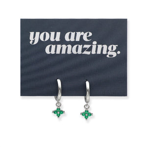 Silver earrings with green stones on a card that says 'you are amazing'.