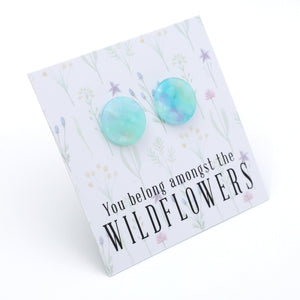 A pair of round, marbled turquoise and light blue stud earrings displayed on a white floral backing card that reads 'You belong amongst the WILDFLOWERS'.