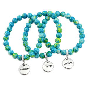Stone bracelets with blue and green stone beads and silver charms with the words 'strength', 'loved', and 'inspire' on them.