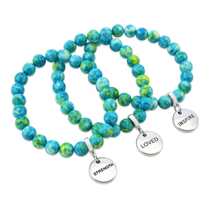A set of three bracelets with blue and green stone beads and silver charms with the words 'strength', 'loved', and 'inspire' on them.