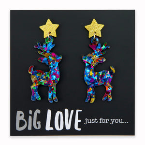 A pair of colorful acrylic and resin dangle earrings featuring glittery reindeer shapes with star accents, displayed on a black background with the text 'BIG LOVE just for you.