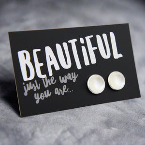 White pearl coloured circle shaped earring studs with silver surround presented on a card that says 'Beautiful just the way you are'