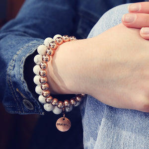 Girl wearing white marble howlite bead braclet with rose gold clip and grateful charm with rose gold stacker bracelet. Bracelet Duo set.