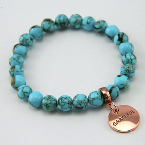 Teal coloured stone bracelet with word charm and rose gold clip.