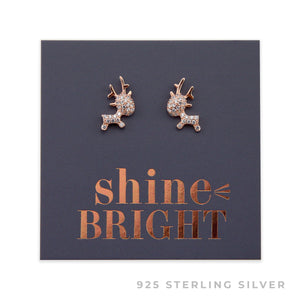 A pair of rose gold sterling silver reindeer stud earrings with cubic zirconia stones, presented on a dark background with 'shine bright' written in gold.