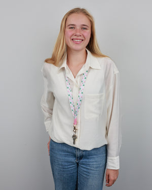 Model wearing the Christmas Delight lanyard over a white shirt, showing its length, colourful Christmas tree print and clasp holding keys.