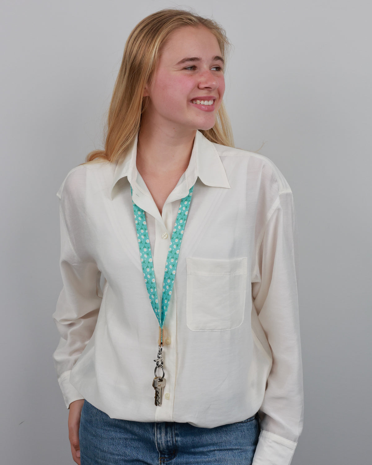 Model wearing the Aqua Daisies lanyard over a white shirt, showing its length and clasp holding keys.