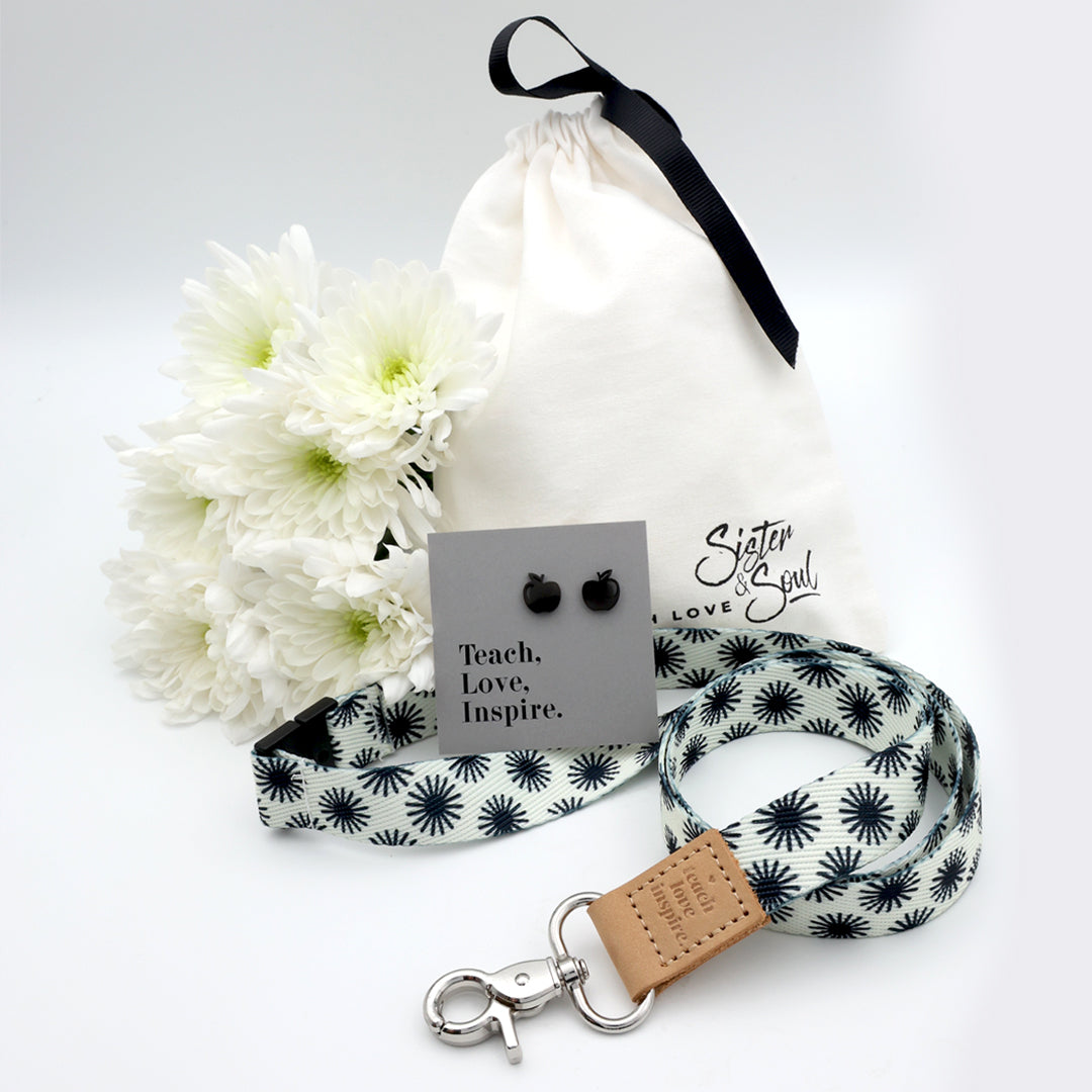 Product set with white flowers, drawstring bag, black and white patterned lanyard, and earrings on a white background.