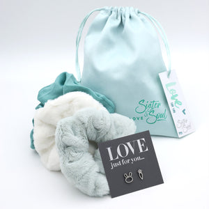 Turquoise and white textured bags with a drawstring bag, card, and tag on a light gray background.