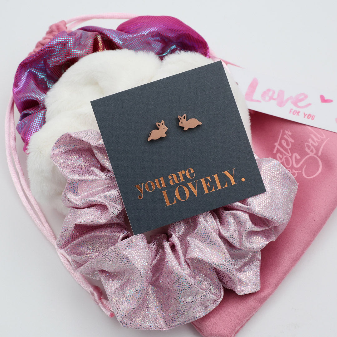 Earring box with 'you are LOVELY' text and bunny earrings on a pink textured background