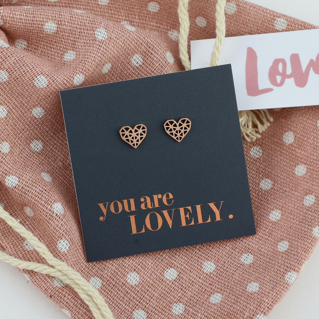 Heart-shaped earrings on a card with 'you are LOVELY.' text, on a polka dot fabric background.