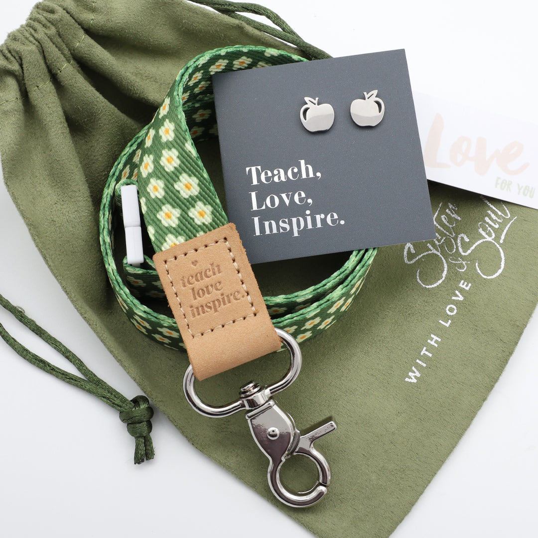 Green floral lanyard with leather tag, earrings, and card on a white background