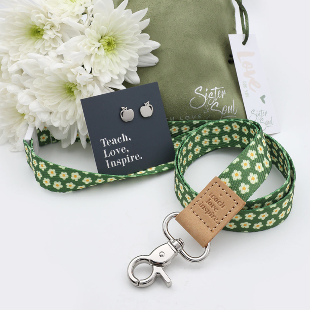 Green floral lanyard with leather tag, earrings, and card on a white background
