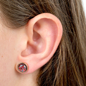 Close-up of an ear wearing a round earring with a colorful design.